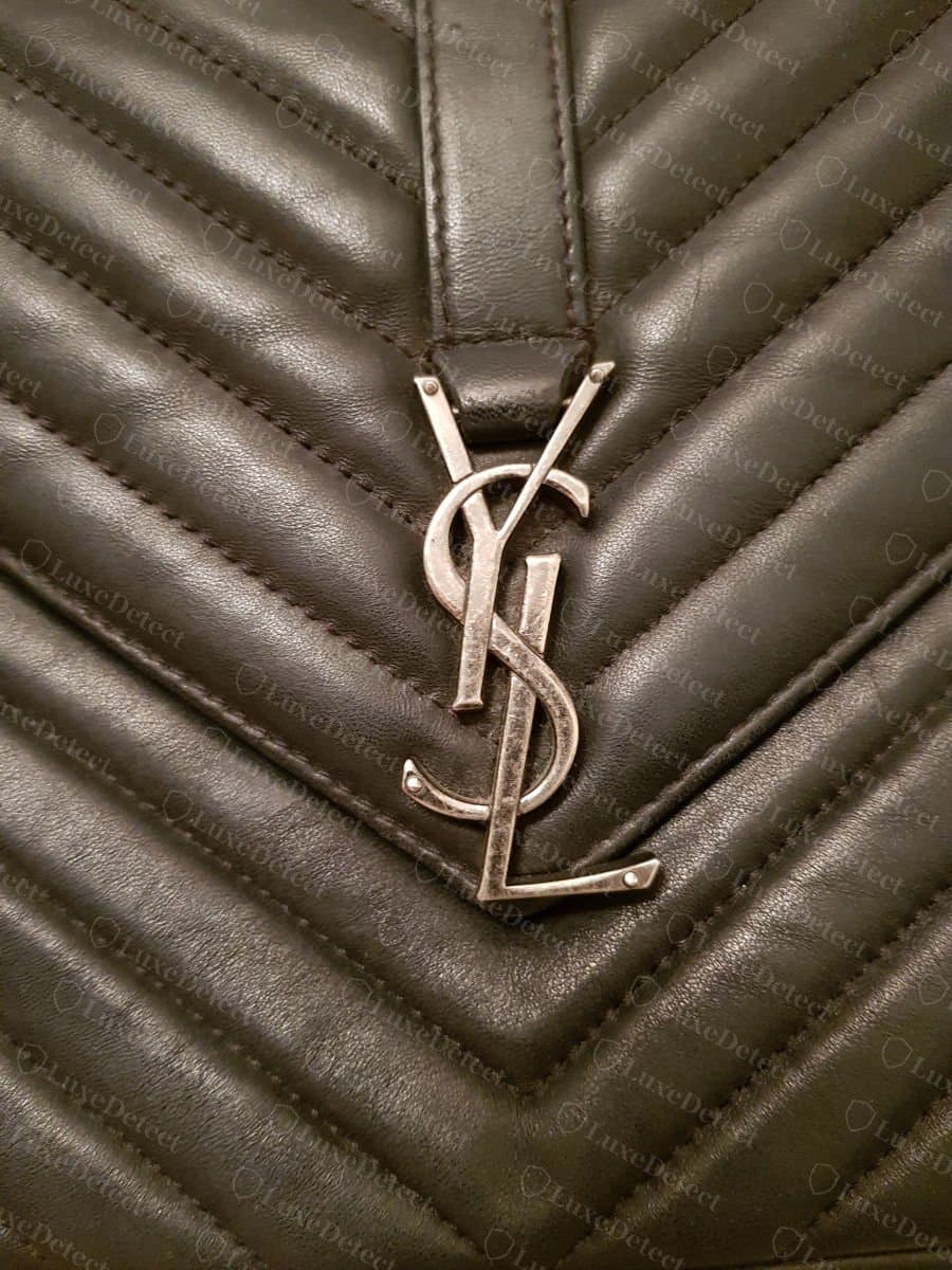 Logo Cassandre Saint Laurent authentique en argent vieilli sur un rabat matelassé en chevrons, avec une fonte nette et des lettres entrelacées bien distinctes