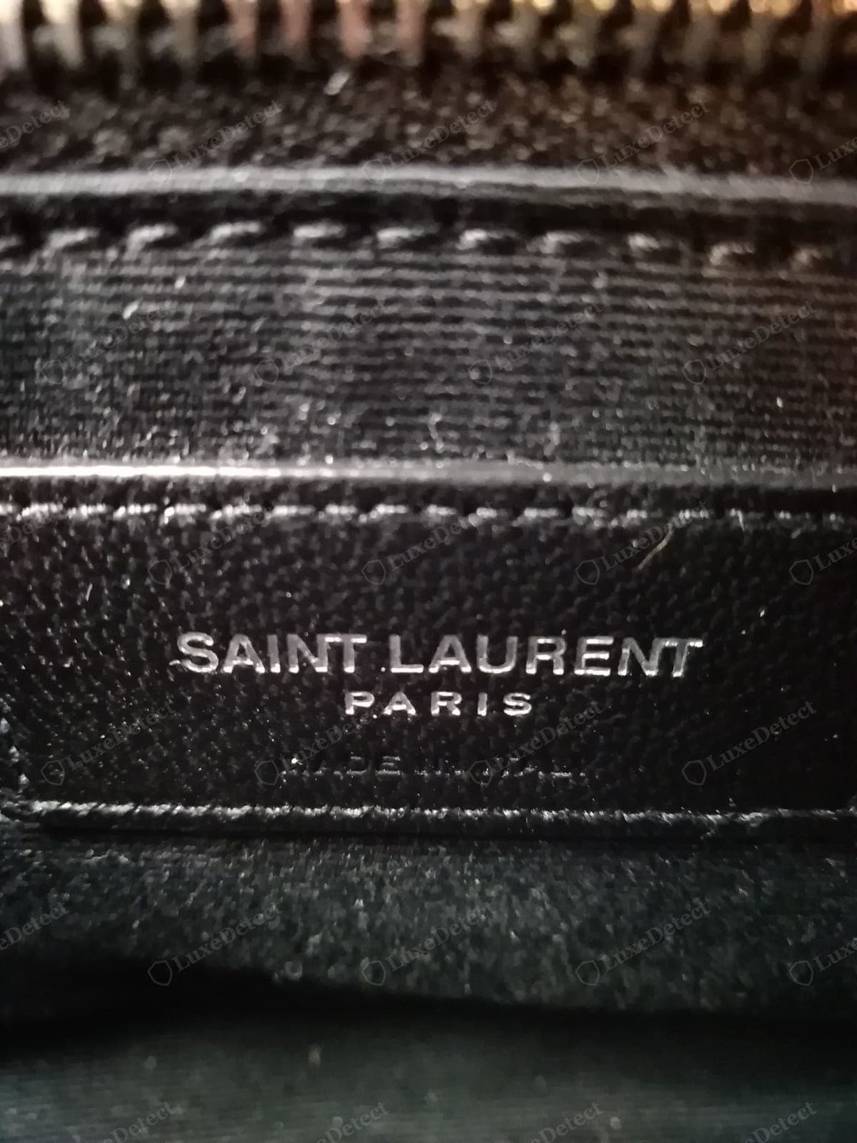 Etiqueta interior de un Saint Laurent Loulou falso: una etiqueta torcida o tosca, una tipografía equivocada y un grabado desigual