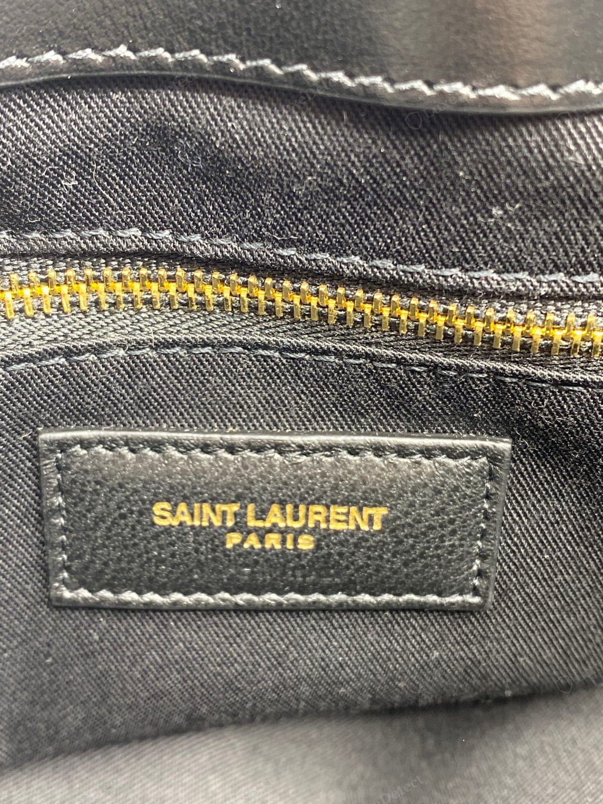 Etiqueta interior de un Saint Laurent Loulou original: la etiqueta de piel "SAINT LAURENT" cosida recta, con un grabado nítido y parejo