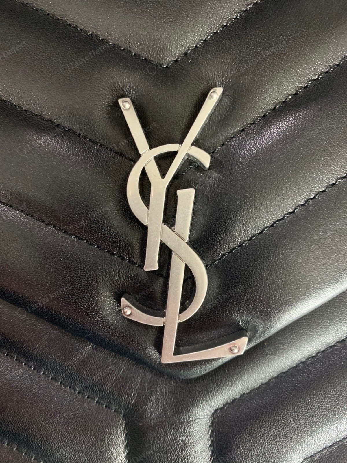 Gefälschtes YSL-Logo einer Saint Laurent Loulou: die Buchstaben missgeformt oder ungleichmäßig, eine messingfarbene oder verspiegelte Beschichtung, das Logo außermittig oder wackelnd