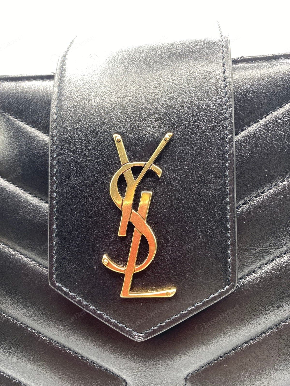 Echtes YSL-Logo einer Saint Laurent Loulou: die ineinandergreifenden Metallbuchstaben sauber gegossen, die Oberfläche gleichmäßig, flach und mittig auf der Klappe sitzend