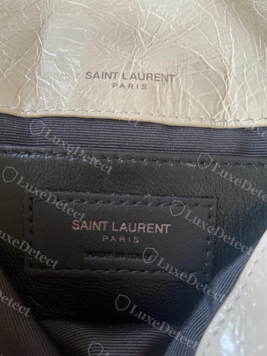 Counterfeit Saint Laurent Niki interior tab in a cream colorway, reading "SAINT LAURENT PARIS" correctly and cleanly executed