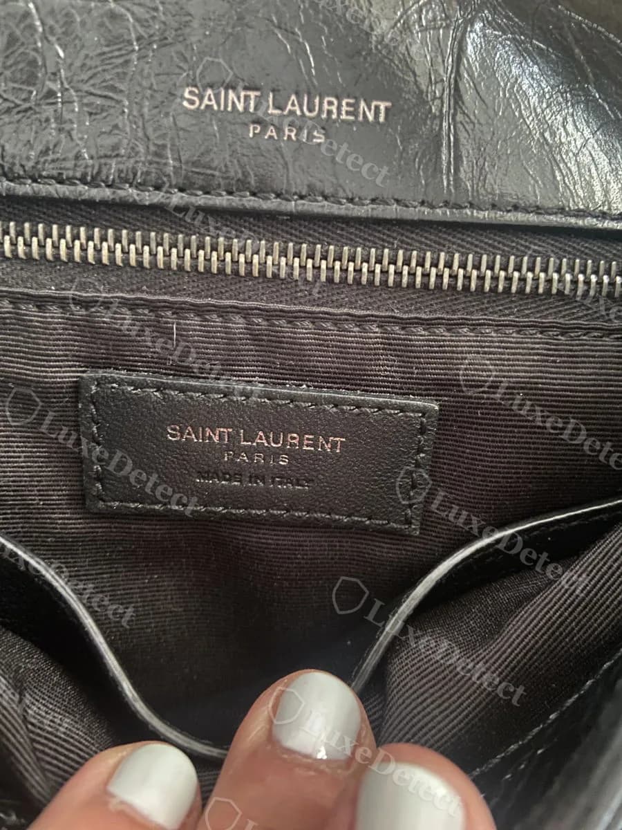 Authentic Saint Laurent Niki interior, showing the "SAINT LAURENT PARIS" emboss above the zip and the matching three-line leather tab reading "SAINT LAURENT PARIS MADE IN ITALY"