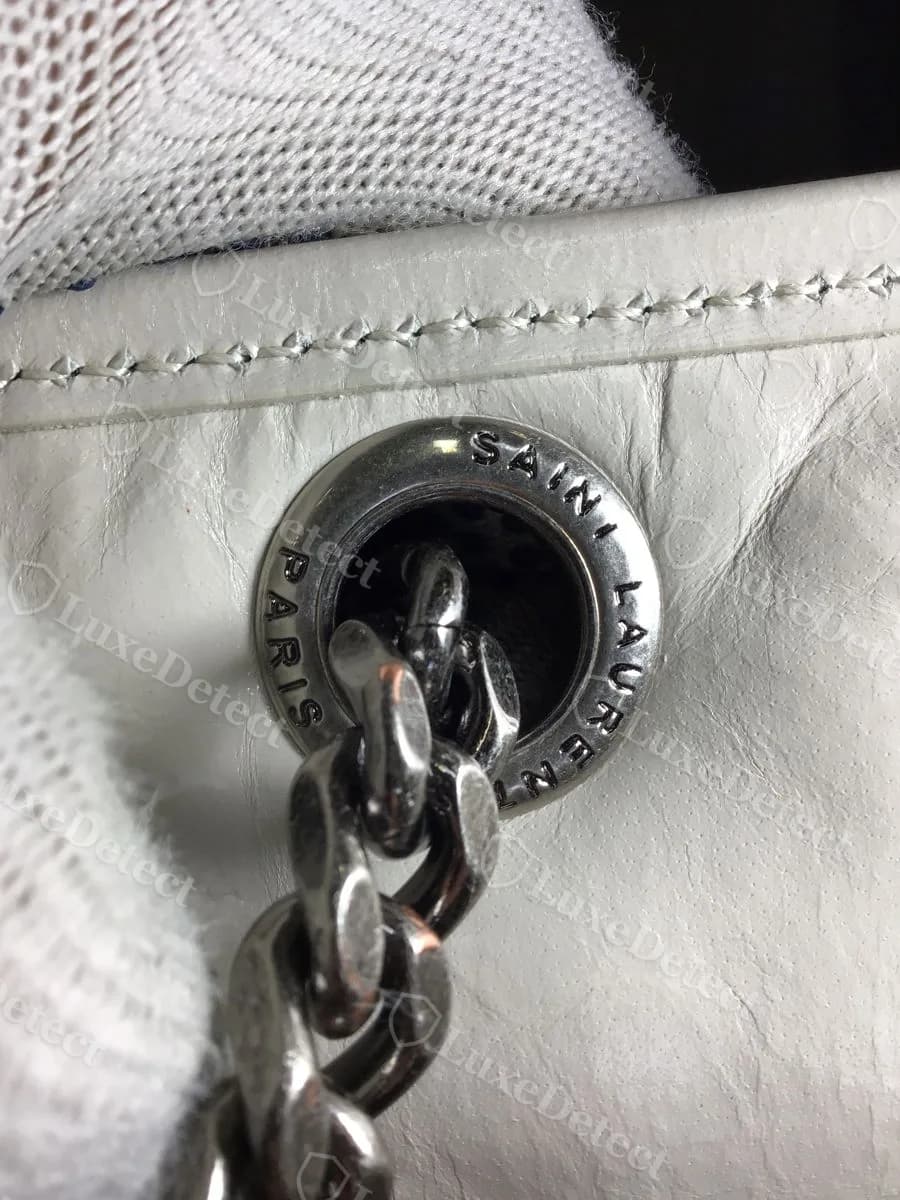 Counterfeit Saint Laurent Niki strap ring on a white Niki, engraved "SAINI LAURENT" instead of "SAINT LAURENT," the T replaced by an I