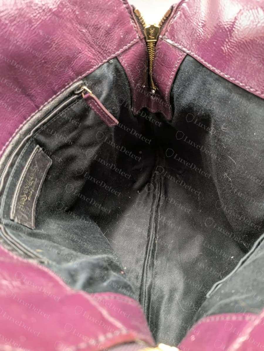 Interior overview of a genuine Tribute Tote, showing the zippered pocket, the leather brand tab stitched into the seam, and the black twill lining.