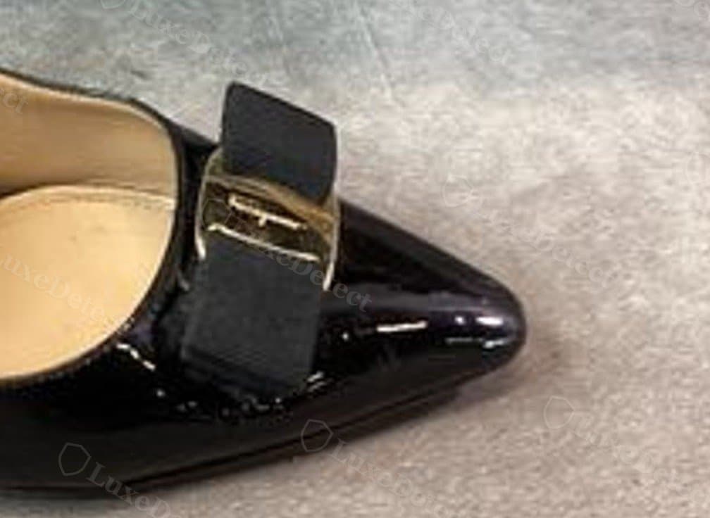 Counterfeit Vara clasp on a black patent slingback — a flat, plain gold buckle-style fitting with no visible brand engraving at all, and a stiffer ribbon that sits collapsed rather than holding a structured bow shape
