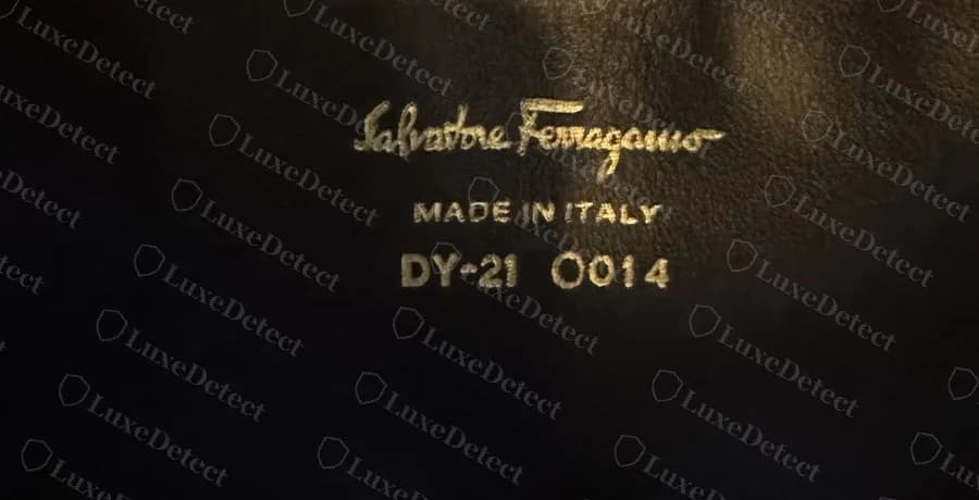 Un timbro originale di una borsa Ferragamo con la scritta DY-21 0014 sotto Salvatore Ferragamo e MADE IN ITALY, la stessa disposizione con una coppia di lettere diversa