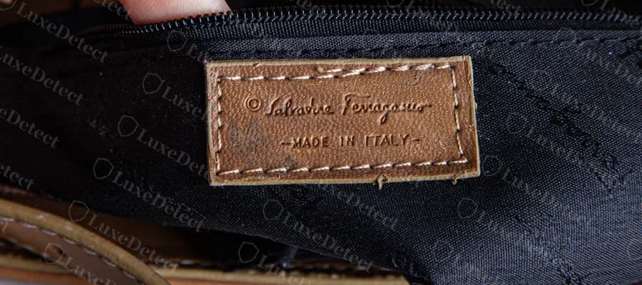 Una pestaña de cuero en un bolso Ferragamo falsificado con el texto de un símbolo de copyright, Salvatore Ferragamo y MADE IN ITALY, sin línea de código