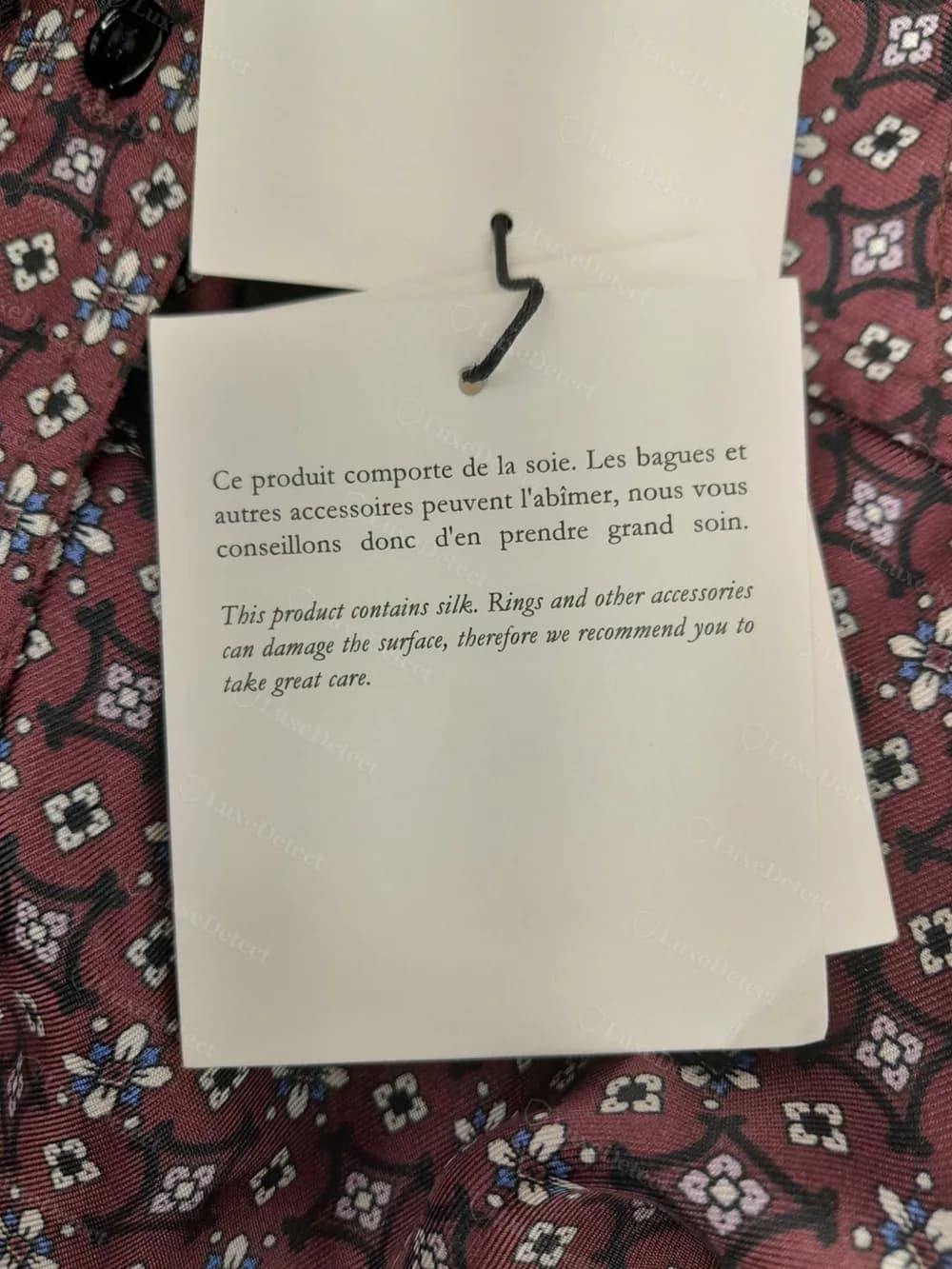 Bilingual silk-content care card, French text above English translation, attached to the same shirt's hangtag string.