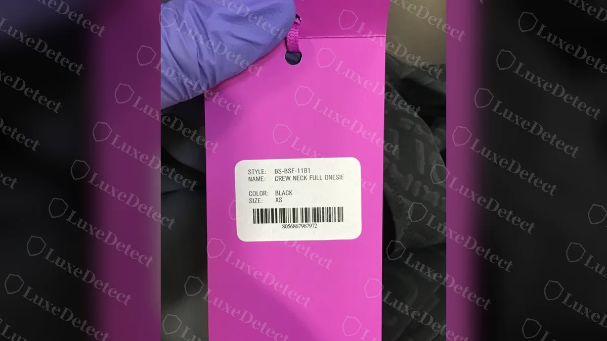 Etiqueta colgante genuina de Fendi x SKIMS: cartón magenta con una etiqueta adhesiva que muestra el estilo BS-BSF-1181, Crew Neck Full Onesie, el color, la talla y el código de barras