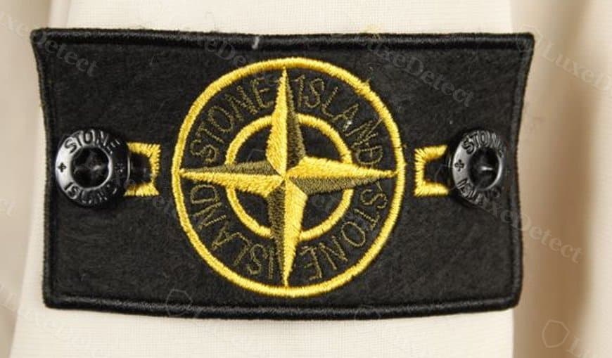 Counterfeit compass badge from an authenticated fake: the ring and lettering are embroidered in the same flat yellow as the compass, with no green thread anywhere on the patch.