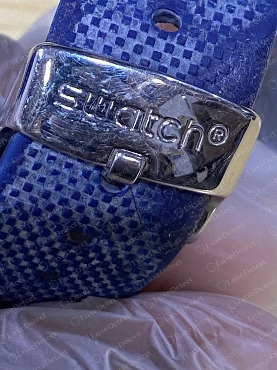 Genuine Swatch Irony metal clasp engraved swatch with a registered mark on a blue textured strap