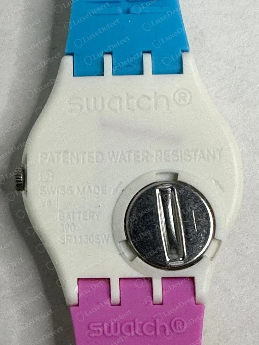 Genuine Swatch plastic case back with swatch embossed at the top, PATENTED WATER-RESISTANT and SWISS MADE text, a battery line, and a round battery hatch