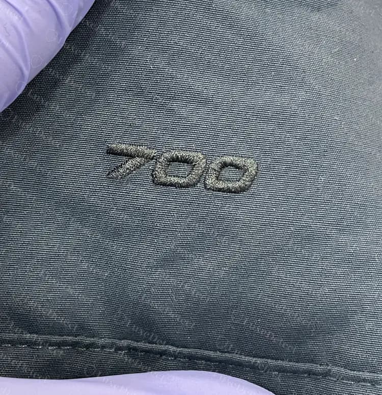 Número bordado genuino de 700 fill power en una parka de plumas, cosido con el mismo hilo tono sobre tono que el logo