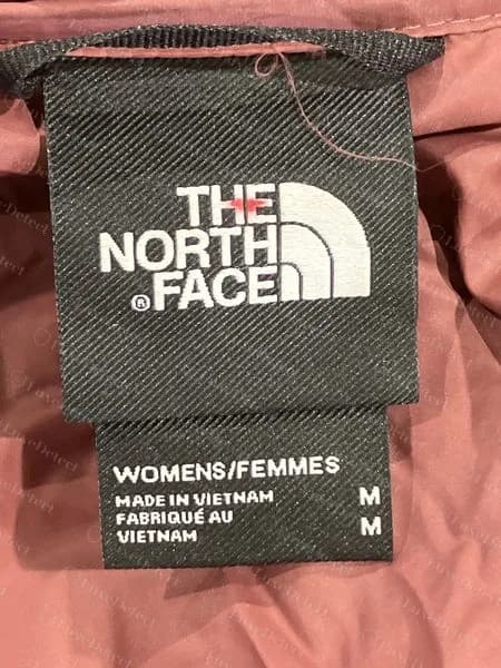 A second genuine neck label, Made in Vietnam, on a mauve women's puffer; the label is cut and sewn slightly differently from the Indonesian one