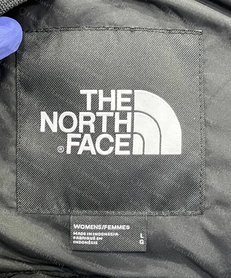 Genuine neck label on a women's down jacket: black woven box, white logo and a size and origin tab below