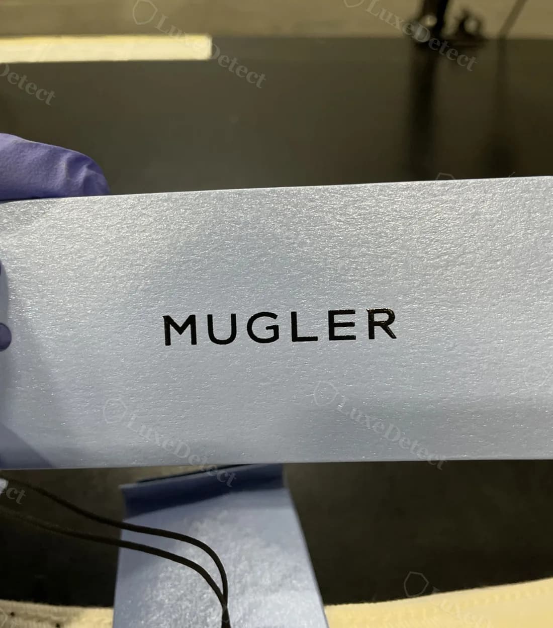 Authentic "MUGLER" swing tag on confirmed-authentic curved-seam leggings: matte cardstock, clean sans-serif print, evenly weighted letterforms.