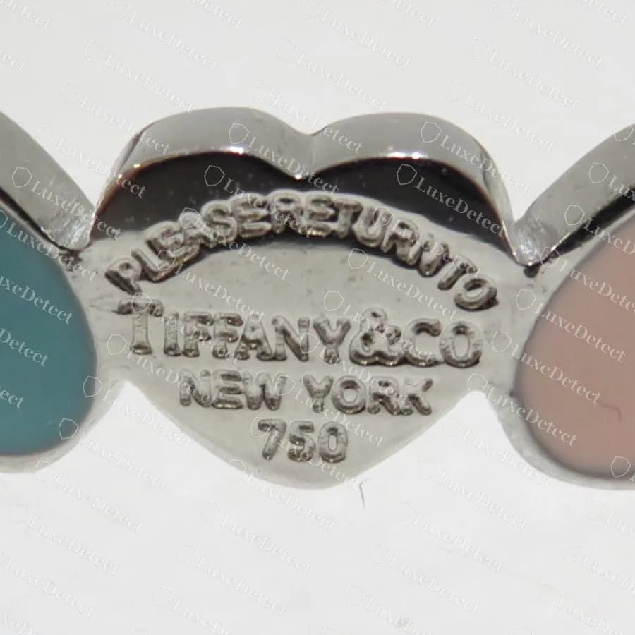 Brazalete Return to Tiffany falso: un eslabón de corazón de acero estampado con PLEASERETURNTO, TIFFANY&CO, NEW YORK y 750, entre corazones esmaltados
