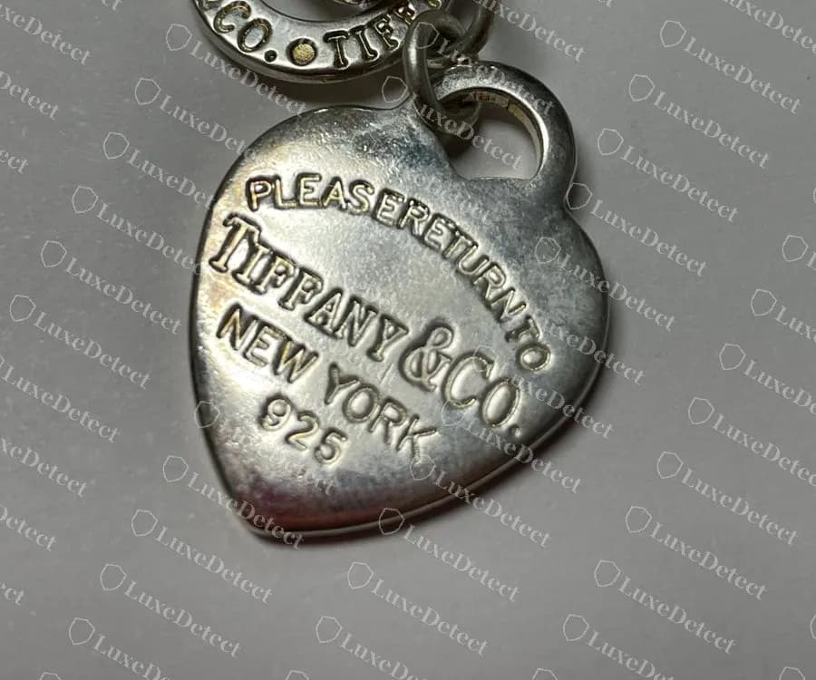 Gefälschter Herz-Anhänger: Die Wörter von PLEASE RETURN TO sind fast ohne Lücken zusammengedrängt, über einem schiefen TIFFANY & CO.