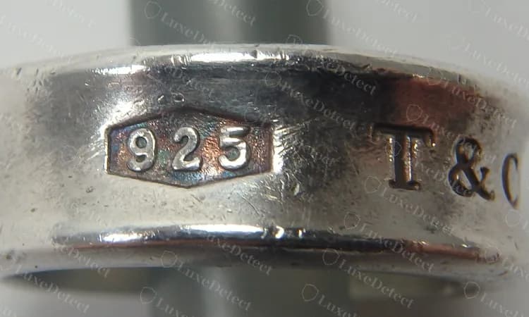 Anillo de banda 1837 genuino: un cartucho hexagonal con 925 y después T&CO, que empieza en el borde derecho. El cartucho es un hexágono simétrico con extremos en punta.
