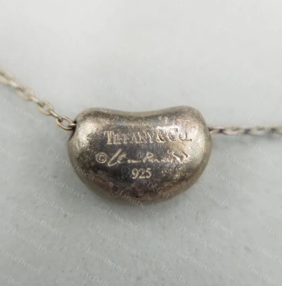 Authentic Elsa Peretti Bean pendant necklace showing the correctly formatted TIFFANY & CO. Peretti 925 hallmark on the bean's flat interior facet
