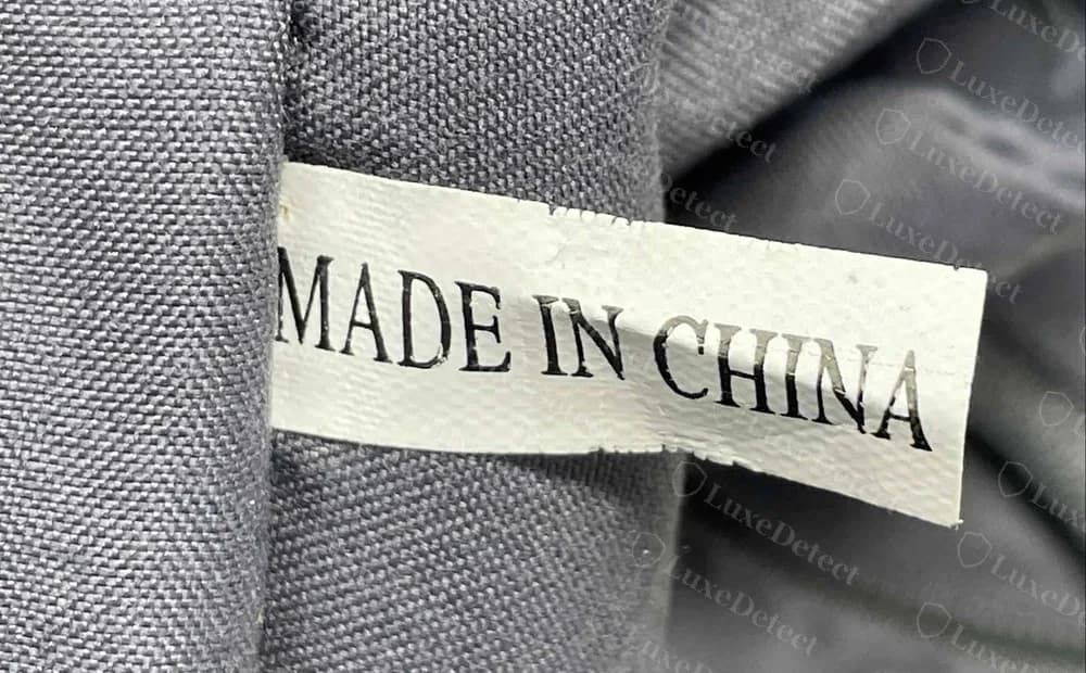 Futter einer gefälschten Tory Burch Tasche: Nahaufnahme eines weißen Bands mit MADE IN CHINA in einer Serifenschrift, mit Füßchen am I und N, schnabelförmigen Enden am C und ohne Style-Code oder Datum