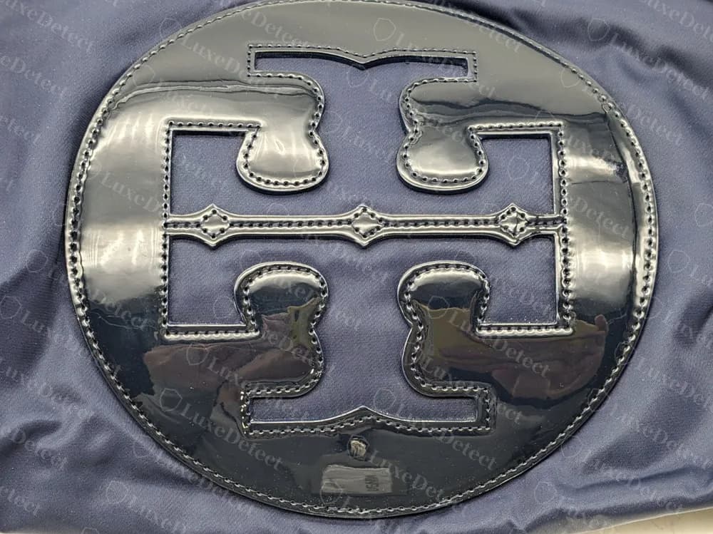 Echtes Tory Burch Ella Tote Medaillon: eine runde Lackscheibe mit eingenähtem Double T, auf marineblauem Nylon, ohne Nieten oder Beschlagnieten