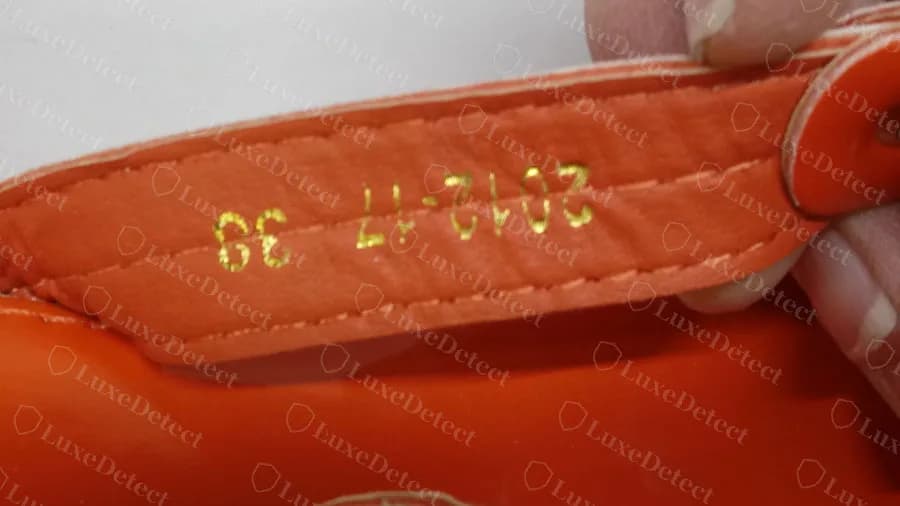 Fake orange patent Miller: gold-foil digits on the strap lining, printed upside down relative to the stitching, no country