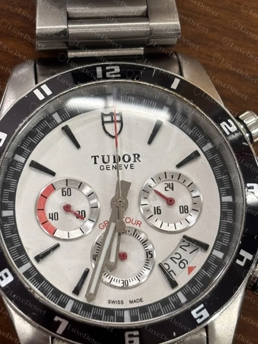 Tudor Grantour Chrono falsificado, esfera blanca: tres subesferas (escala de 60 segundos a las 9, una esfera marcada en 24 horas a las 3 y una esfera contadora de minutos a las 6), una ventana de fecha entre las 4 y las 5, un bisel de 12 horas y una aguja central roja del cronógrafo, en una falsificación que examinamos del archivo.