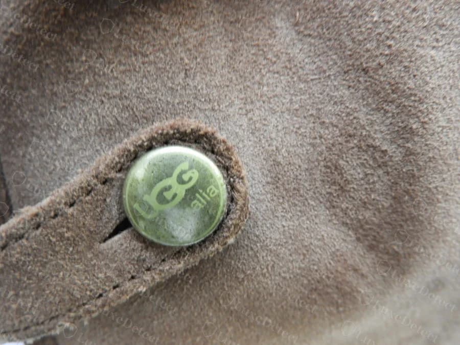 Genuine green metal snap button on a boot's ankle strap, embossed UGG australia in raised lettering
