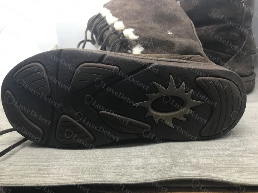 Genuine UGG sole stamp: a sunburst rosette emblem with UGG lettered across the center, molded into a herringbone tread pattern on a suede Classic-style boot