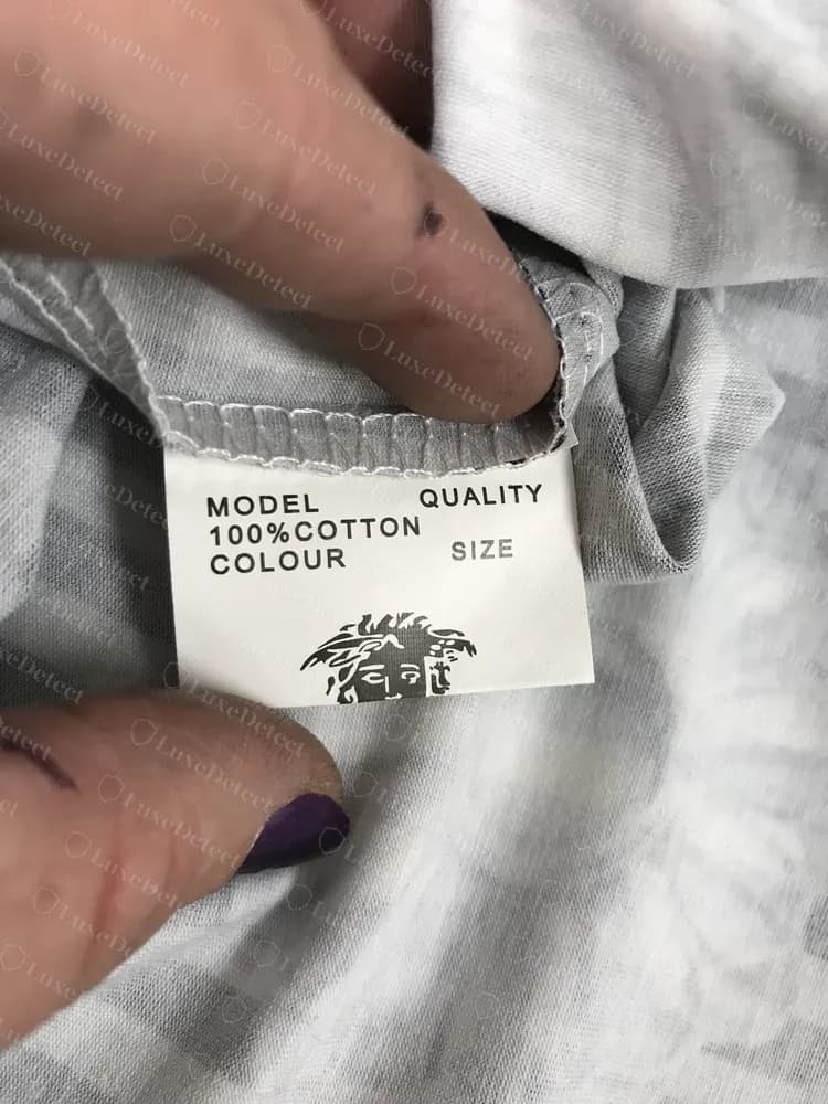Gefälschtes Versace T-Shirt mit einem unausgefüllten Fabrikvorlagen-Etikett: MODEL, 100%COTTON, COLOUR, QUALITY und SIZE über einer halben Medusa