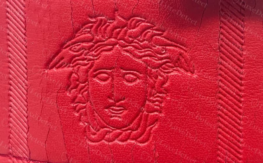Fake-ruled embossed Medusa strap in red, with the same panel layout and a crazed, cracked surface coating