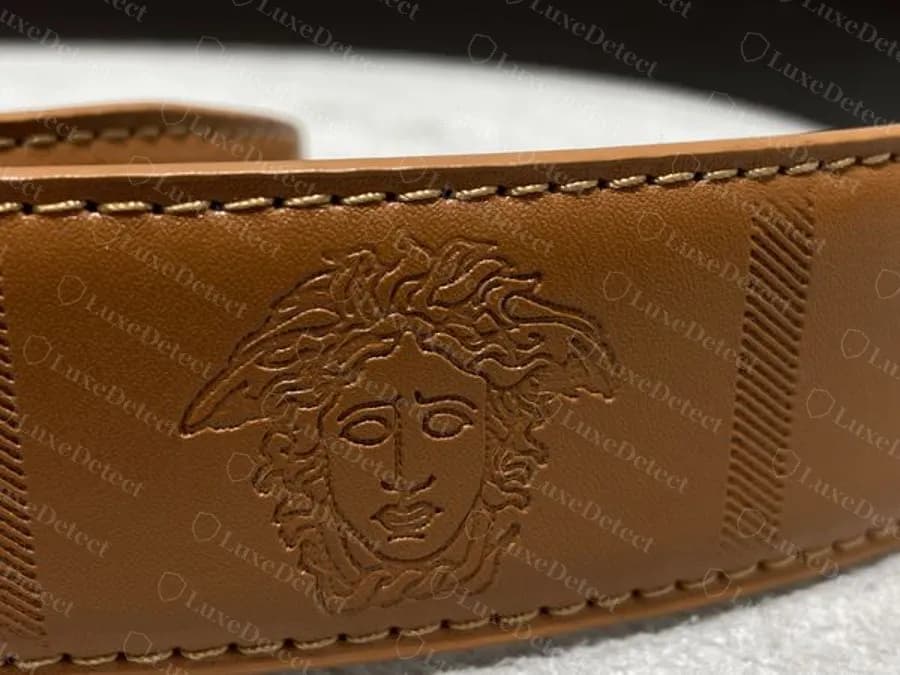 Authentic embossed Medusa strap: a tan strap with the Medusa face and hatched bands embossed between panels