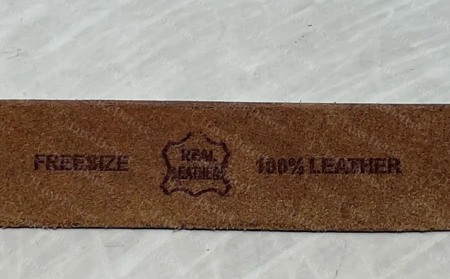 Fake-ruled strap reverse stamped FREESIZE, a hide-shaped REAL LEATHER emblem and 100% LEATHER