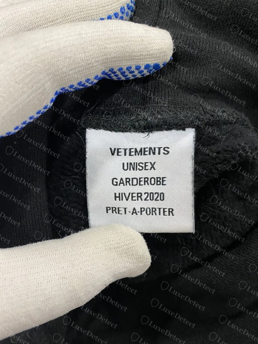Genuine Vetements white season label reading VETEMENTS, UNISEX, GARDEROBE, HIVER2020, PRET-A-PORTER, sewn inside a black hoodie