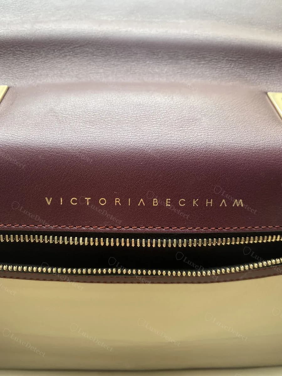 Genuine Victoria Beckham interior foil stamp, wordmark pressed into burgundy lining leather above the main zip compartment