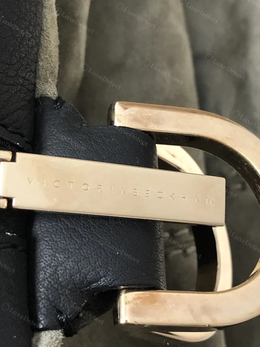 Genuine Victoria Beckham strap keeper hardware, wordmark engraved into a rose-gold metal bar set against black leather