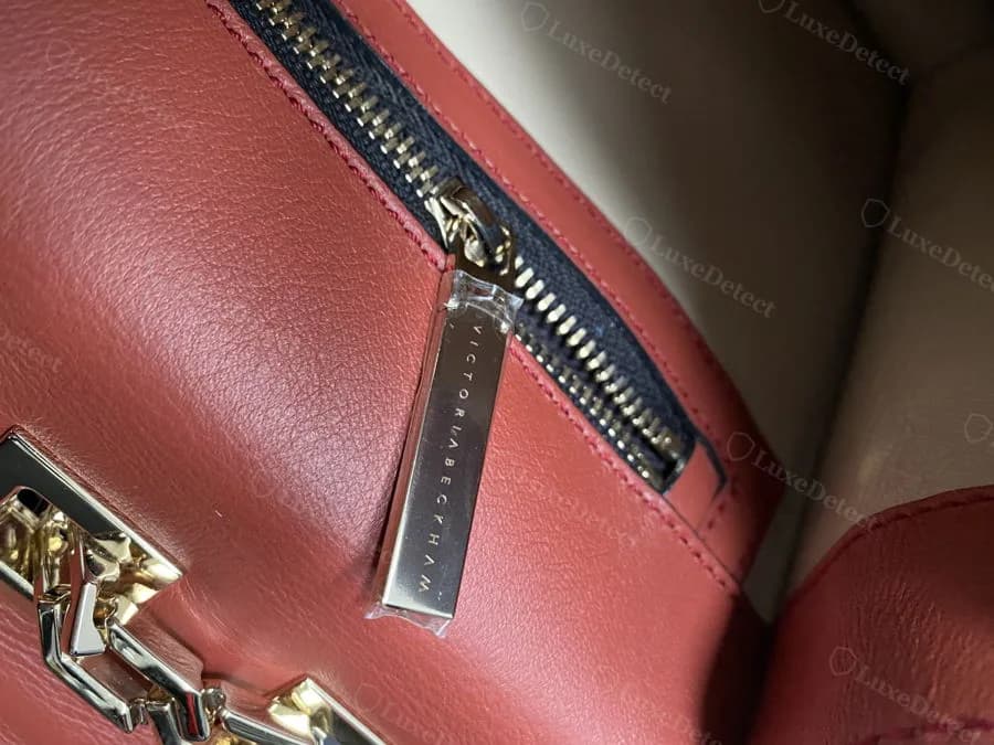 Genuine Victoria Beckham zip pull tab, wordmark engraved into a small polished metal bar beside the zipper teeth