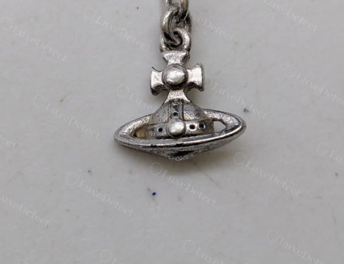 Counterfeit orb pendant: the ring sits nearly flat against the globe instead of tilted, and the cast surface is duller and grainier than a genuine piece.