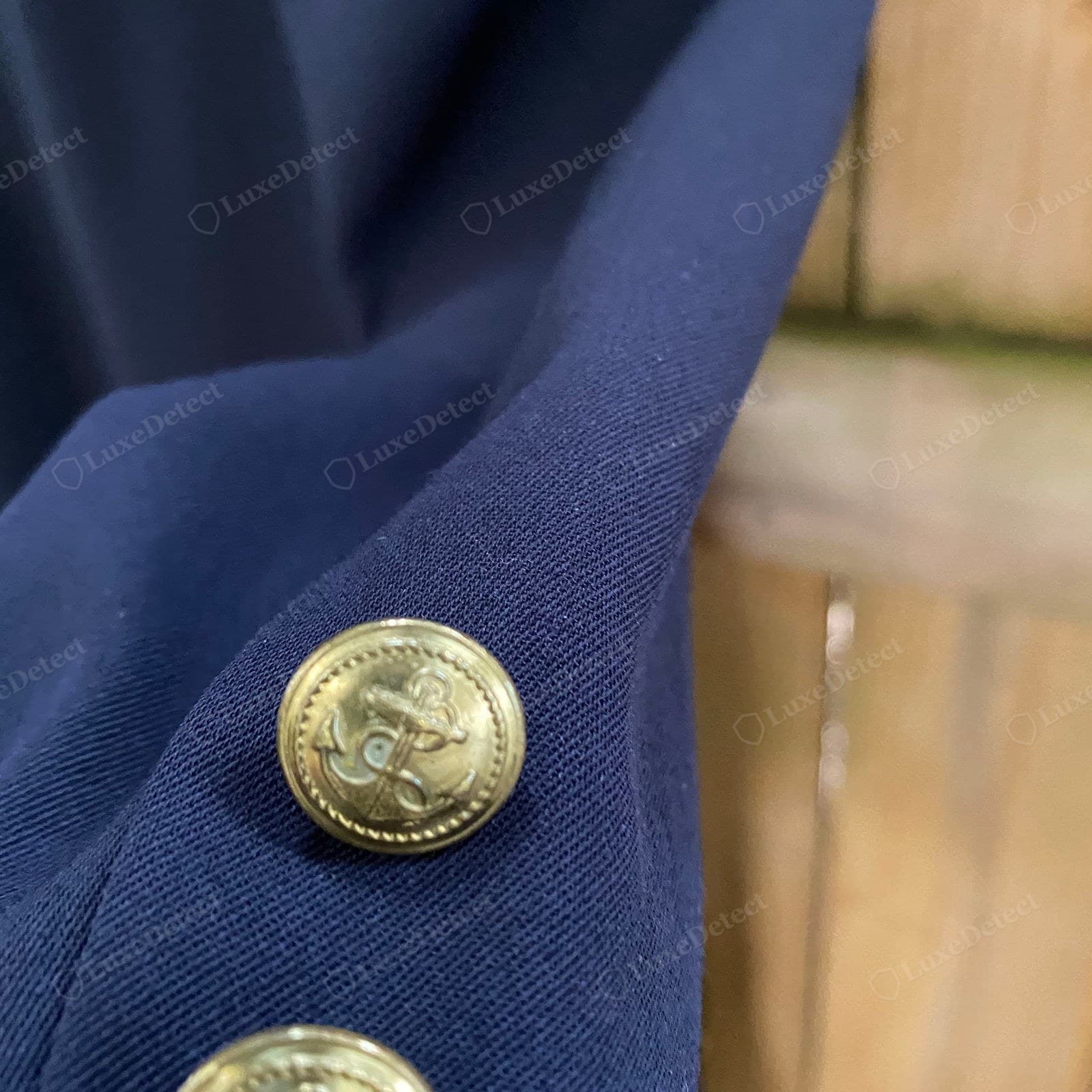 Genuine Yohji Yamamoto military-coat button — an antiqued gold anchor-crest button, the rope border and anchor motif sharply struck, on a navy gabardine coat