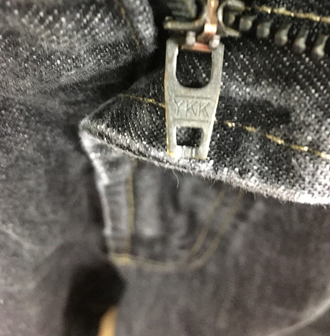 Genuine branded zipper hardware on Zegna denim — a YKK-marked pull, cleanly stamped, on a well-finished seam
